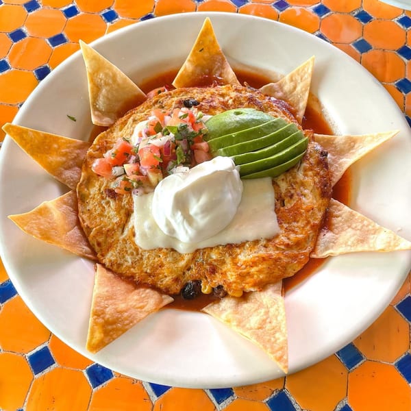 Lazy Daisy's breakfast omelet with salsa, avocado, sour cream, and tortilla chips on a colorful table.